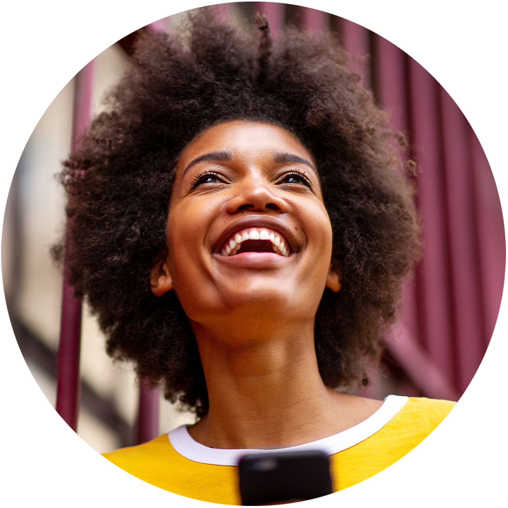 a photo of a woman holding her phone and laughing while looking off into the distance