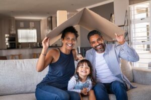 A family of three sits on a couch together while holding a piece of cardboard over their heads and wondering what is internal family systems