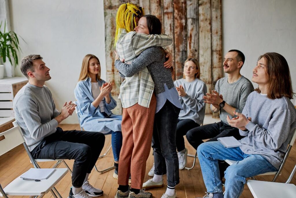 two people in group therapy hug after they made stress disorder treatment preparations