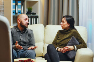 a person in schizophrenia disorder treatment sits on a couch with a therapist talking 